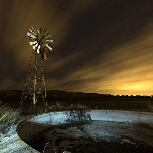 A metal tower windmill at night