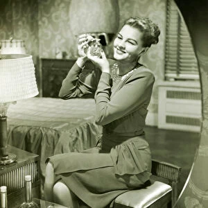 Mirror reflection of woman applying perfume at vanity table, (B&W)