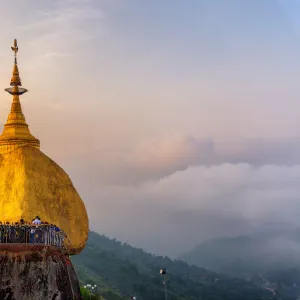 Morning Landscape sunrise view with fog of Kyaiktiyo pagoda (Golden Rock) at twilight with praying people and tourists. Kyaiktiyo, Myanmar