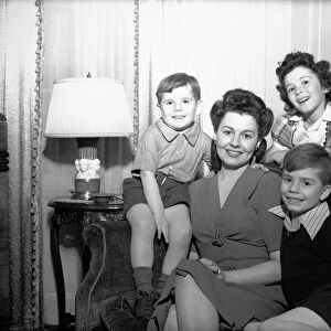 Mother with three children (4-5, 6-7, 8-9) posing in living room, (B&W), portrait