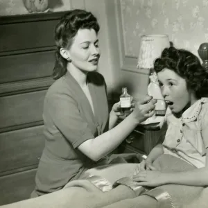 Mother giving medicine to girl