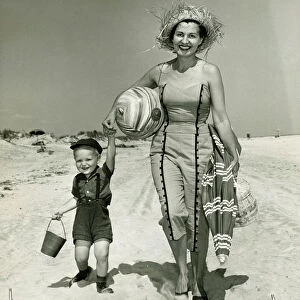 Mother with son (2-3) walking on beach, (B&W), portrait