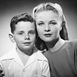 Mother with son (6-7) posing in studio, (B&W), portrait