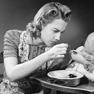 Mother trying to feed unwilling baby (9-12 months), (B&W)