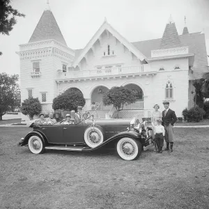 Multigeneration family in car and outside car in front of house