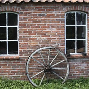 Old wagon wheel on a facade, brick stone, East Frisia, Lower Saxony, Germany, Europe
