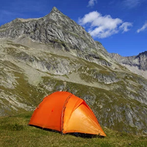 Orange-coloured mountain tent below the summit of Wiwanni Mountain in the Pennine Alps, Valais, Switzerland, Europe