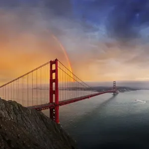 Panoramic view of the Golden Gate Bridge with a rainbow at sunset and orange-glowing storm clouds, San Francisco, California, United States Panoramic view of the Golden Gate Bridge with a rainbow at sunset and orange-glowing storm clouds, San Francisco, California, United States