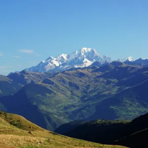 The pass road leading up to Col de la Madeleine, the snow-capped peaks of the Mont Blanc Massif at the back, Alps, France