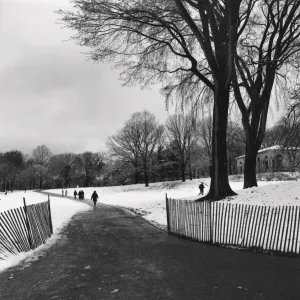 People walking on a path through a snow covered park People walking on a path through a snow covered park