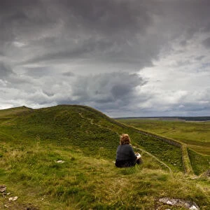 A Person Sits On A Hill With A View Of Hadrians Wall