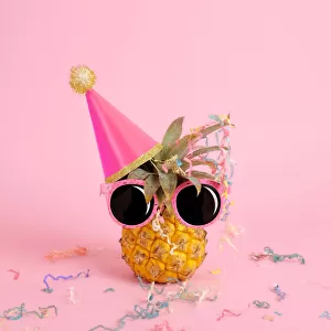 Pineapple wearing a party hat and sunglasses