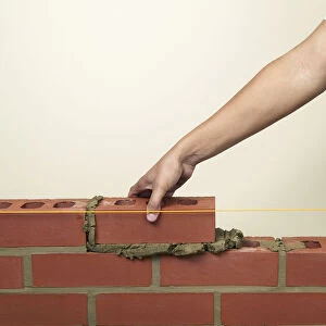 Placing a new brick on to fresh mortar on a wall