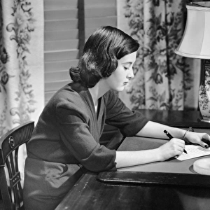 Portrait of woman writing letter at desk