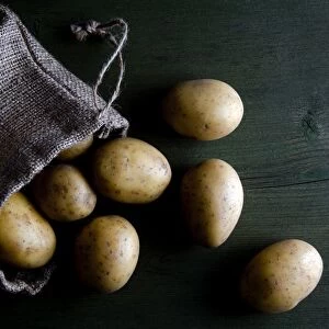 Potatoes in burlap sack on wood