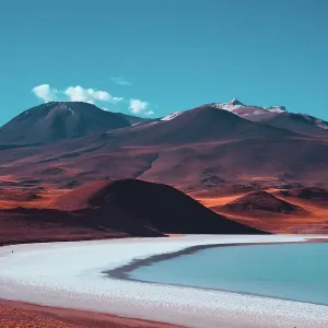 Red volcanic mountains and a blue salt lake. Beautiful nature background Red volcanic mountains and a blue salt lake. Beautiful nature background