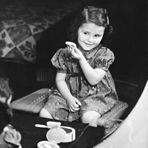 Reflection of girl (4-5) sitting in front of mirror, applying face powder (B&W), elevated view