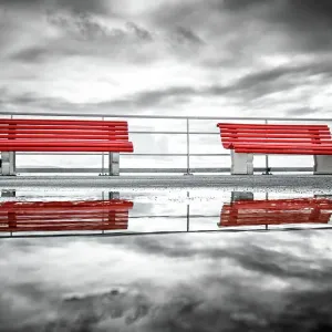 Reflection of two red benches in a puddle on La pier du Moulleau, La Teste-de-Buch, France Reflection of two red benches in a puddle on La pier du Moulleau, La Teste-de-Buch, France