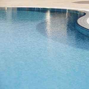 Rippled water surface in a swimming pool, detail, blue with steps below the surface