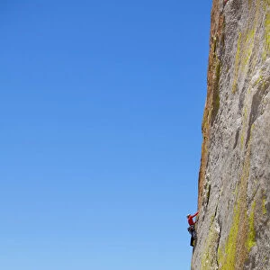 Rock climber climbing steep face of rock cliff