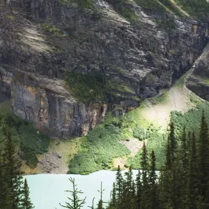 Rock face over green lake and pine trees, with interesting light Rock face over green lake and pine trees, with interesting light