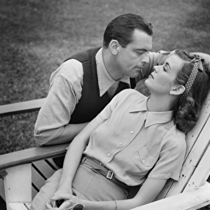 Romantic couple relaxing on deckchair, (B&W)