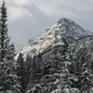 Rugged mountain peak with snow under a cloudy sky Rugged mountain peak with snow under a cloudy sky
