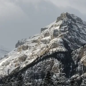 Rugged mountain peak with snow under a cloudy sky Rugged mountain peak with snow under a cloudy sky