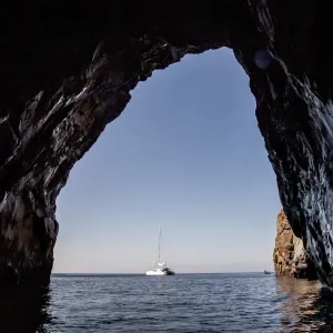 Sailboat viewed from cave in ocean Sailboat viewed from cave in ocean