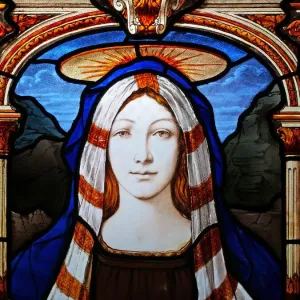 Sainte Marie voilée et couronnée sur une fenêtre de verre coloré abandonnée. Sainte Marie voilée et couronnée sur une fenêtre de verre coloré abandonnée.