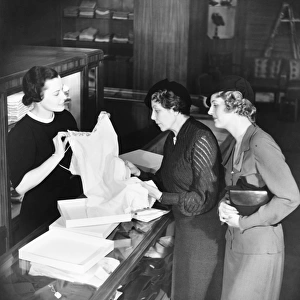 Sales clerk presenting lingerie to clients (B&W)