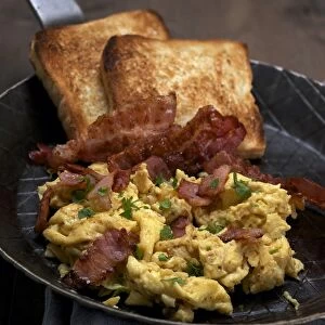 Scrambled eggs with fried bacon and toast