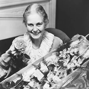 Senior woman holding boxed flowers, (B&W), portrait
