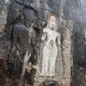 Shrine of Mahayana Buddhism, three old Buddha statues as rock reliefs, Avalokiteshvara in white, larger Buddha on the right, Buduruvagala, Wellawaya, Monaragala Distrikt, Sri Lanka
