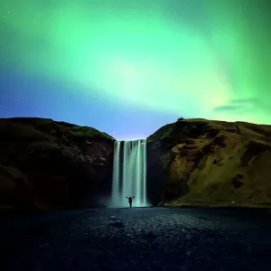 silhouette women and Skogafoss waterfall with Northern Light or Aurora Borealis, Iceland waterfall travel nature famous tourist destination silhouette women and Skogafoss waterfall with Northern Light or Aurora Borealis, Iceland waterfall travel nature famous tourist destination
