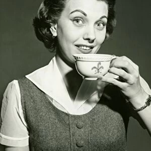 Smiling woman holding cup, posing in studio, (B&W), portrait