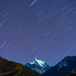 Snowy mountain peak and Star trail in Yading