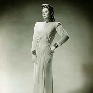 Sophisticated woman in evening gown posing in studio, (B&W), portrait