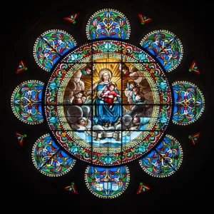 La fenêtre de vitraux colorés en forme de rose représentant la Vierge Marie et son fils Jésus-Christ. La fenêtre de vitraux colorés en forme de rose représentant la Vierge Marie et son fils Jésus-Christ.