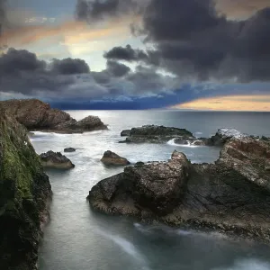 Sunset light rocky coast storm clouds sea Sunset light rocky coast storm clouds sea