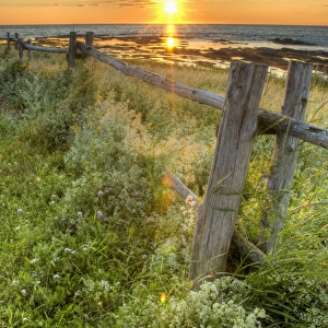 Sunset Over Water And A Fence Along The Shoreline
