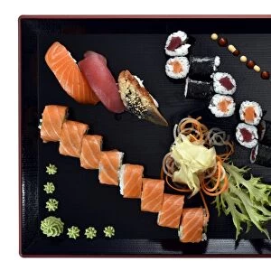 Sushi dish with Maki, Uramaki, Nigiri with salmon, tuna, eel, fresh ginger, wasabi, on a Japanese wooden plate