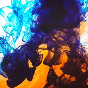 Swirls of spreading orange and blue ink in liquid