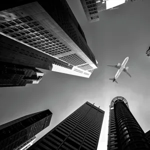 Tall city buildings and a plane flying overhead