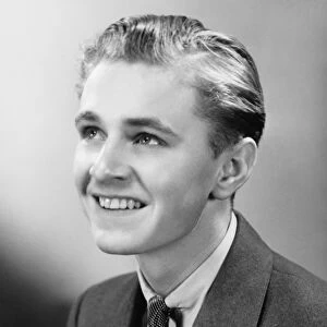 Teenage boy (16-17) smiling, posing in studio, (B&W), close-up, portrait