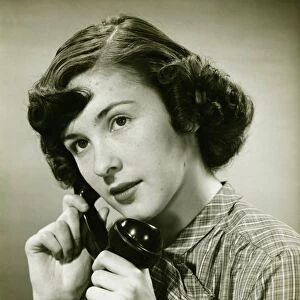 Teenage girl (16-17) on phone posing in studio, (B&W), portrait