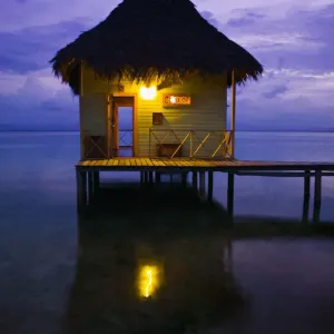Thatch roofed hut at end of dock, dusk
