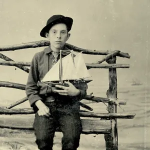 Tintype photograph from 1870s of boy holding a model sailboat