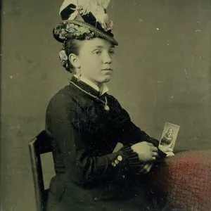 Tintype of woman in feathered hat holding a photograph
