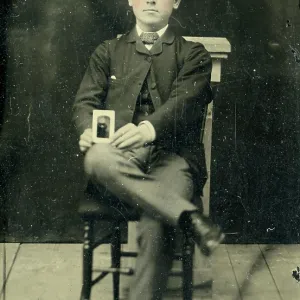 Tinype of young man holding a photograph